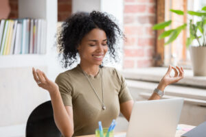 young woman sitting at table opposite laptop in workplace meditating, the changing landscape of lone workers